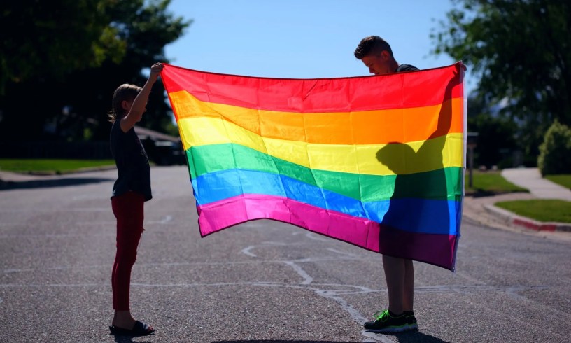 Two people holding up a pride flag
